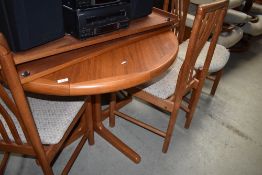 A vintage teak circular dining table and set of six similar railback dining chairs