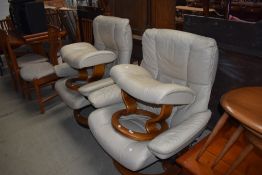 A pair of Stressless armchairs and footstools, in cream leather