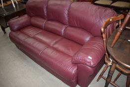 A modern three seater settee in soft burgundy leather