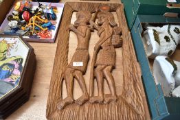A mid century tribal carved hard wood panel depicting ethnic villagers