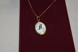 A ceramic pendant for initial M in a yellow metal mount on a 9ct gold box chain, approx 2.6g