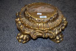 A carved wood style base having lions paw feet and gilt finish