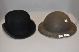 A WW2 era tin hat and a vintage bowler hat.