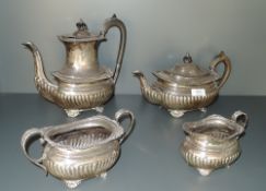 A silver four piece tea set having gadrooned decoration with monogram to side, hard wood handles,
