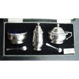 A cased three piece silver condiment set of cauldron form having band decoration and blue glass