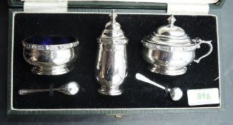 A cased three piece silver condiment set of cauldron form having band decoration and blue glass