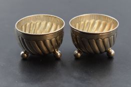 A pair of Victorian silver salts, of circular spirally fluted form with beaded rim, raised on