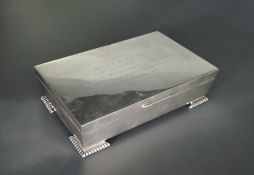 A silver cigarette box of plain casket form having bracket feet and presentation inscription