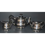 An Edwardian silver three piece breakfast tea set of oval baluster form having hard wood and loop
