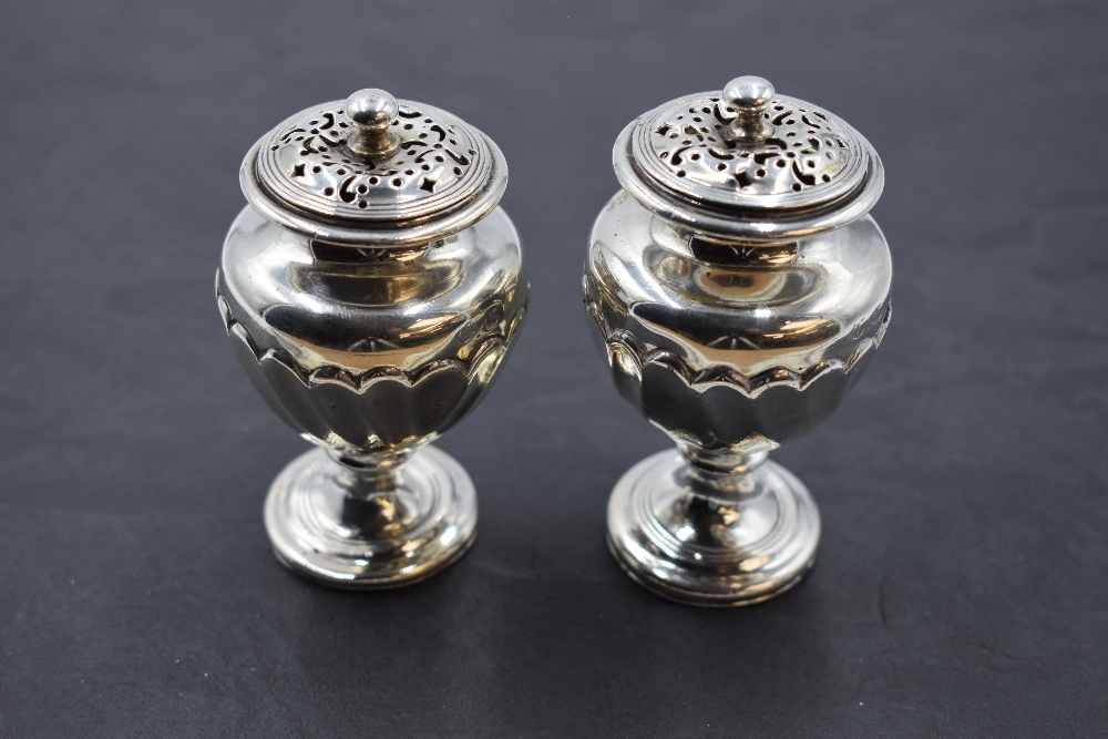 A pair of 19th century silver pepperettes, of urn-form with pierced finial topped pull-off covers