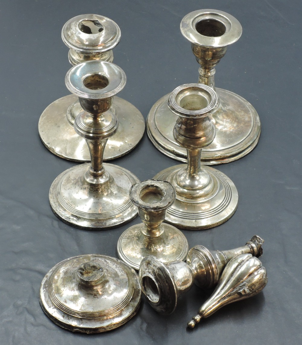 A group of six silver candlesticks, each of differing design, date and maker, damages to all some