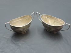 A pair of late Victorian silver salts, of oval twin handled for, with half gadrooned decoration,