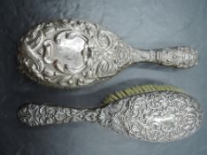 An Edwardian silver back hair brush, embossed with scrolling foliate decoration, marks for London