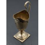 A Georgian silver cream jug of helmet form having loop handle, engraved foliate decoration, pedestal