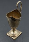 A Georgian silver cream jug of helmet form having loop handle, engraved foliate decoration, pedestal
