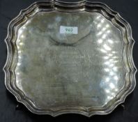 A silver salver having raised pie crust rim, hoof feet and presentation inscription to centre,