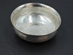 A small eastern white metal dish, of circular form with flared rim, decorated with bands of