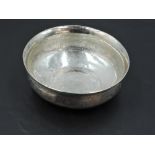 A small eastern white metal dish, of circular form with flared rim, decorated with bands of