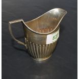 An Edwardian silver cream jug< of helmet form with half fluted body and angular handle, marks for