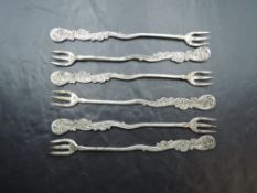 A set of six late Victorian pickle forks, with triple tines, slender stems terminating with rocaille