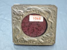 A Japanese white metal or Antimony photograph frame, of canted square form, decorated with dragons