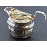 A George III silver cream jug, of helmet form with reeded rim and moulded body with bands of