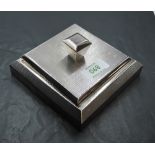 An Art Deco silver table powder box of square form having engine turned decoration, bakelite base