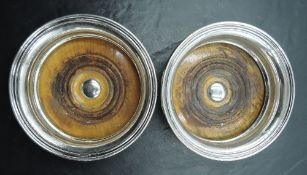 A pair of silver-plated wine coasters, of moulded circular form with turned mahogany interiors