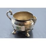 An Egyptian white metal milk jug, of bulbous circular form with scroll handle and animal paw feet,