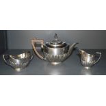 An Edwardian silver three-piece teaset, comprising teapot, sugar and cream, of oval half fluted