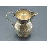 A silver cream jug of plain baluster form having loop handle and pedestal foot, Chester 1935, S