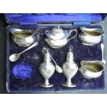 A cased silver condiment set having gadrooned decoration, Birmingham 1912, Joseph Gloster Ltd,