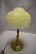 An art deco era table lamp having brass base with mottled yellow and cream glass shade