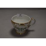 An antique tea cup by Schumann marked SPM to base having gilt and ivy decoration