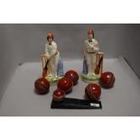 A pair of Staffordshire flat back figures of cricketers and a selection of cricket balls