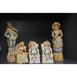 Five porcelain bisque figures including a larger mantle pair and three seated figures