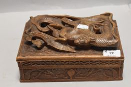 A carved wooden box having compartmental interior of Japanese style depicting dragon consuming