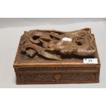 A carved wooden box having compartmental interior of Japanese style depicting dragon consuming