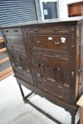 A late 19th Century dark oak cabinet on stand in the Jacobean style, later felt lined shelves to