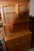 A modern pine kitchen dresser, with glazed upper cupboard doors.