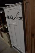 A vintage oak wardrobe on pedestal base being painted shabby chic with bird decoration