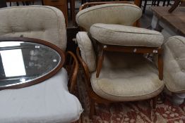 An Ercol stick back three piece lounge suite, comprising two seater settee, armchair and foot stool,