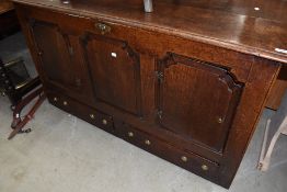 A period oak kist having lift lid and panelled door access via front, with double drawers to base,