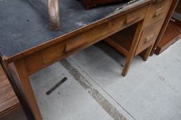 A 1950's oak desk, with long frieze drawer opposed by a bank of three drawers, crudely applied