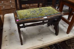 A Victorian mahogany footstool, with serpentine outline and trestle type supports linked by turned