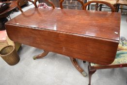 A Victorian drop leaf mahogany table having fluted centre support and brass lions paw feet on