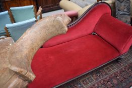 A late Victorian mahogany chaise longue, with raised and shaped back and scrolled arm, raised on