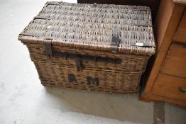 A large late 19th/early 20th century woven wicker hamper with metal straps and locking mechanism,