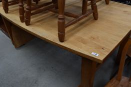 A large modern pine dining table, of shaped rectangular form with end extensions, and raised on
