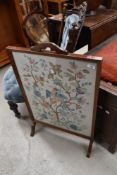An early 20th century wood framed fire screen having embroidery to centre.